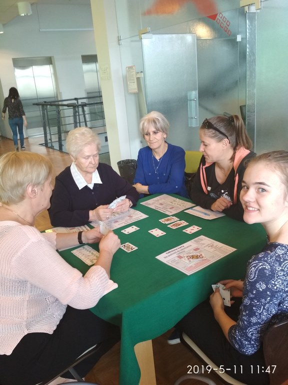Trzy pokolenia przy stoliku brydżowym w Centrum Alzheimera w Warszawie.